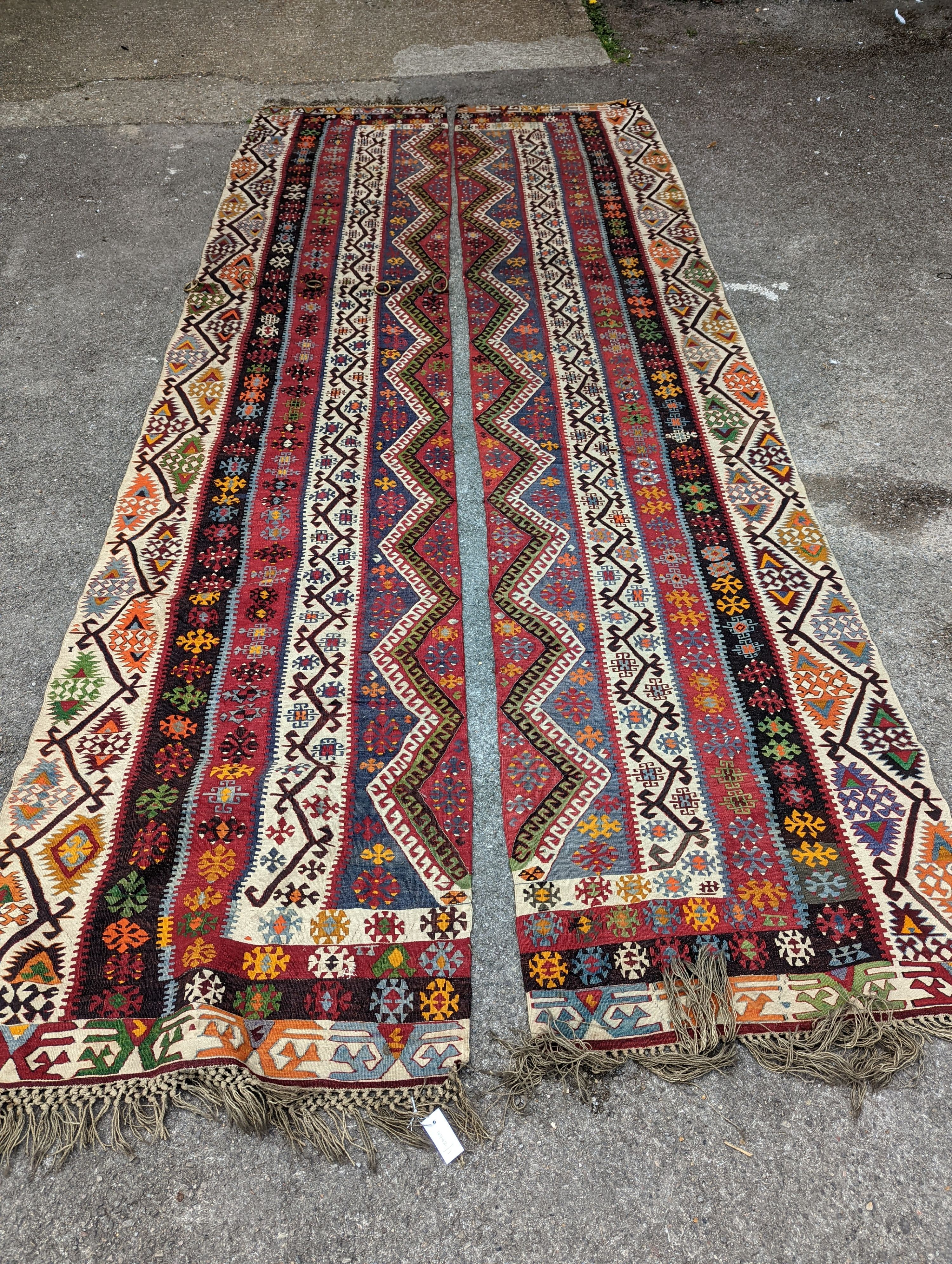 A Kilim polychrome flatweave carpet, cut centrally to create a pair of runners, each 440 x 97cm